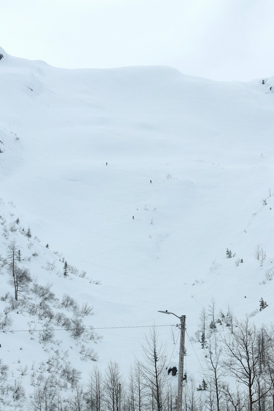 Persone che sciano e fanno snowboard giù per una vasta montagna innevata.