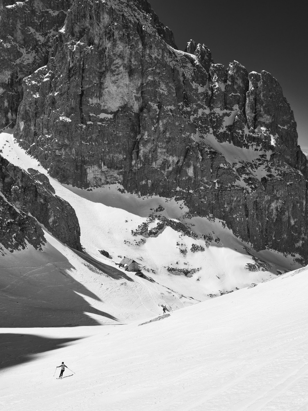 Due persone sciano e fanno escursioni su un pendio montuoso innevato.