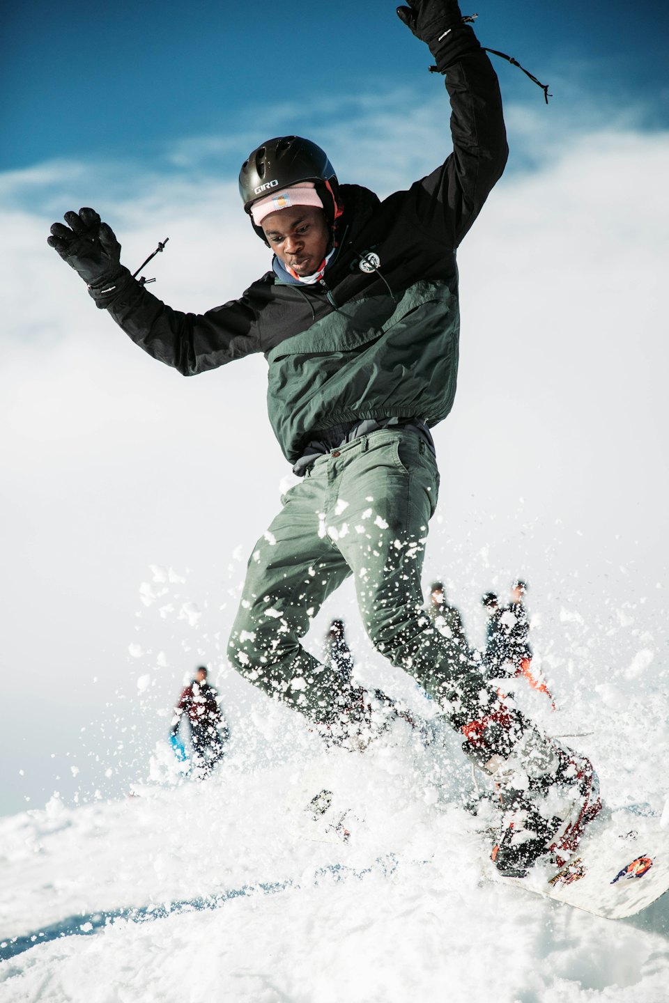 Snowboarder salta in aria sopra un pendio montano innevato.
