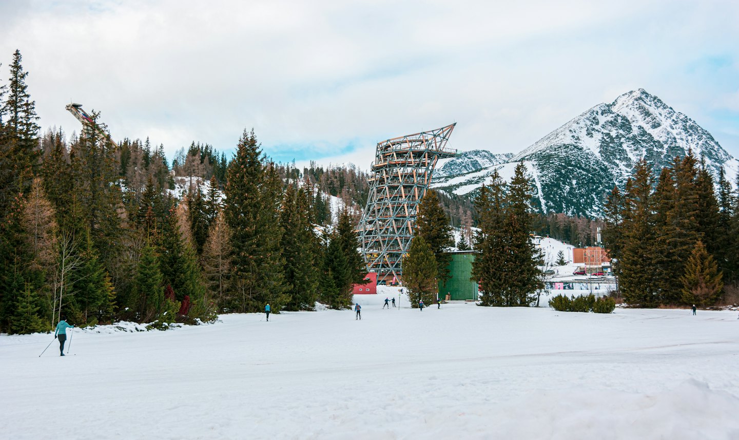 Persone sciano di fondo vicino a una moderna torre di osservazione in inverno.