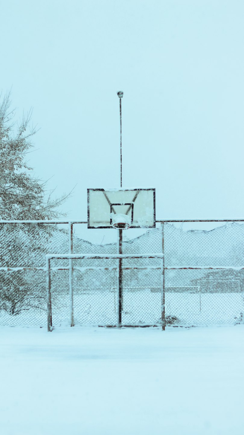 La neve copre il canestro e il campo da basket in inverno.