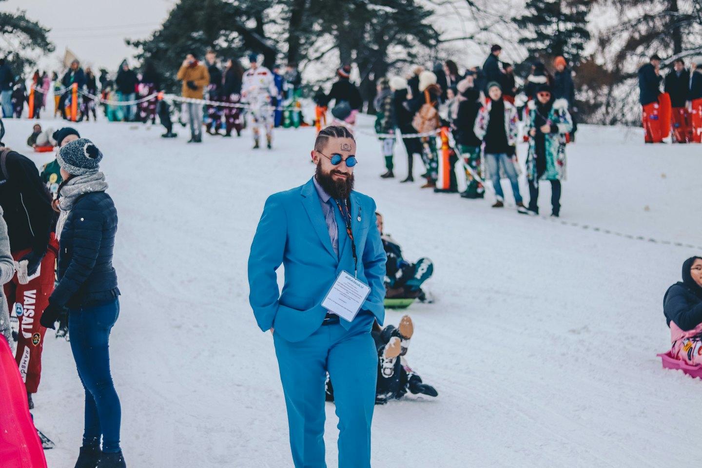 Uomo in abito turchese a un evento all'aperto innevato.
