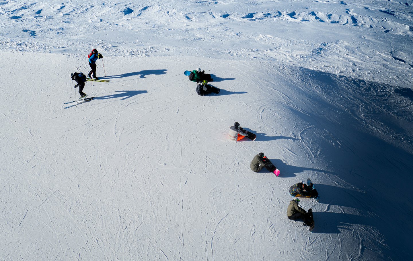 Persone che sciano e fanno snowboard su una montagna soleggiata e innevata.