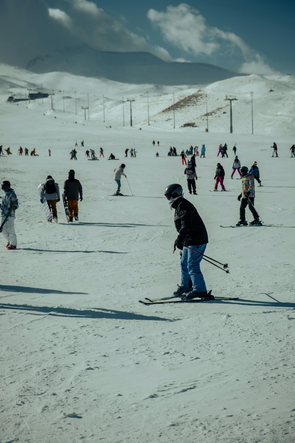 Persone che sciano e fanno snowboard su un pendio montano innevato.
